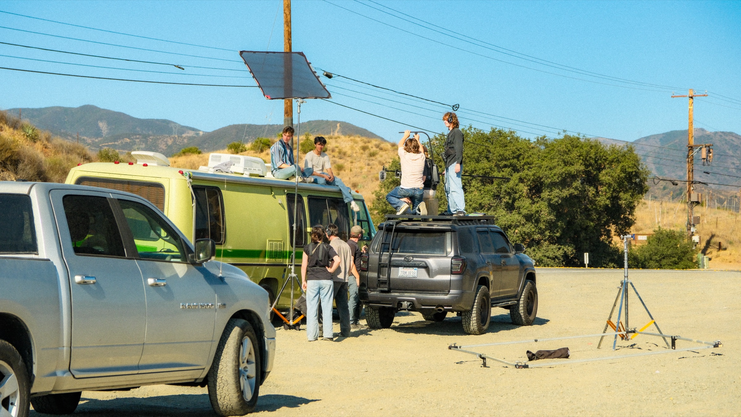 A Drive-Thru film crew shooting around a vintage green RV in the California hills